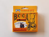BICYCLE × BE@RBRICKのポーカーセット外箱（黄橙のパッケージとベアの自転車イラスト）