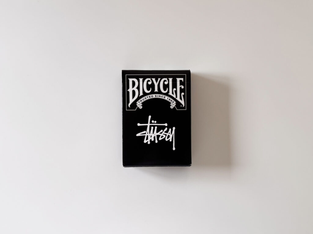 STUSSY × BICYCLEの黒箱デック。ホワイトロゴが映えるパッケージの正面写真